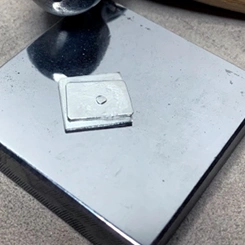 two squares of silver with a rivet through the center