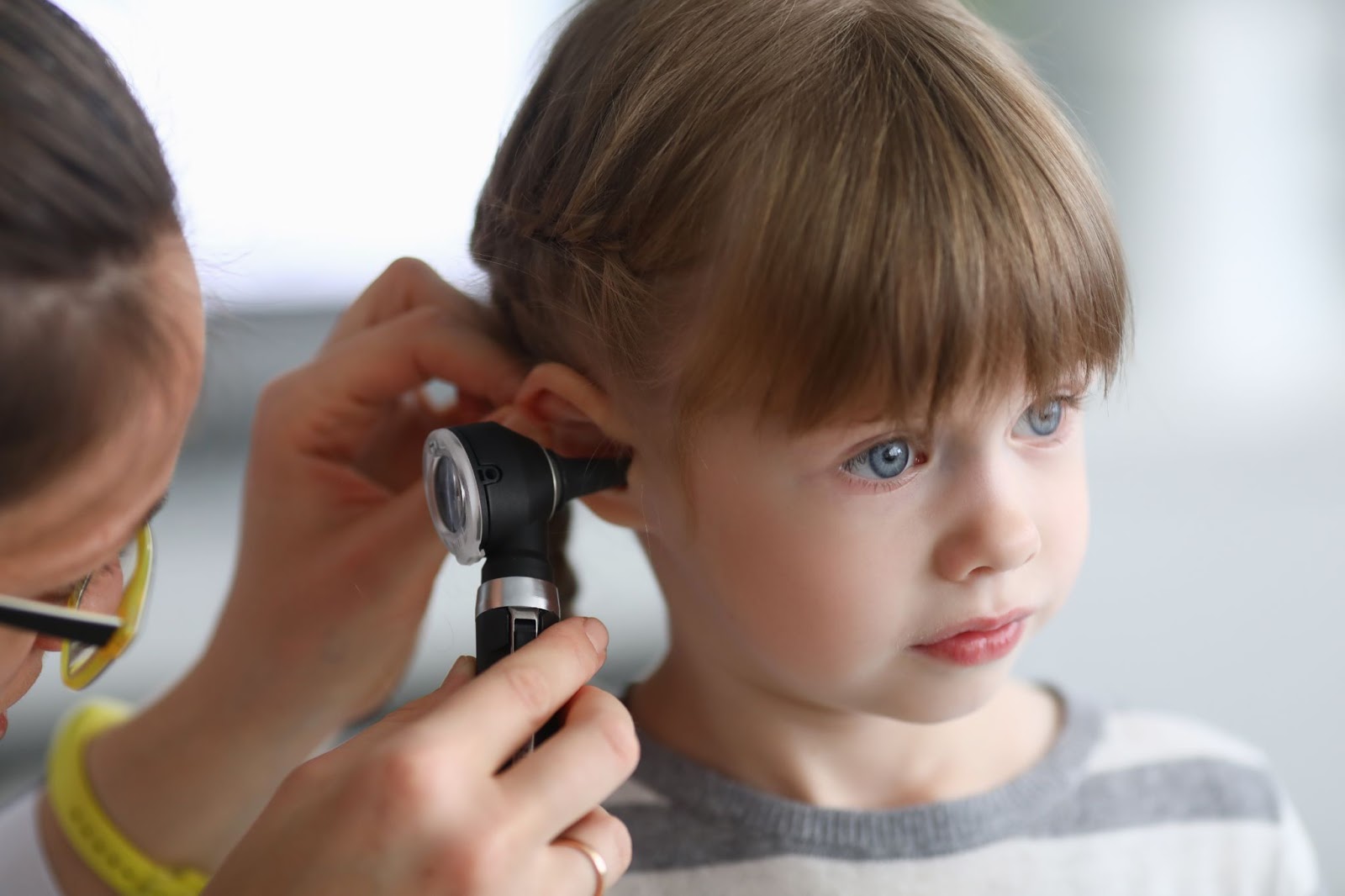 A doctor looks in a little girl's ear
