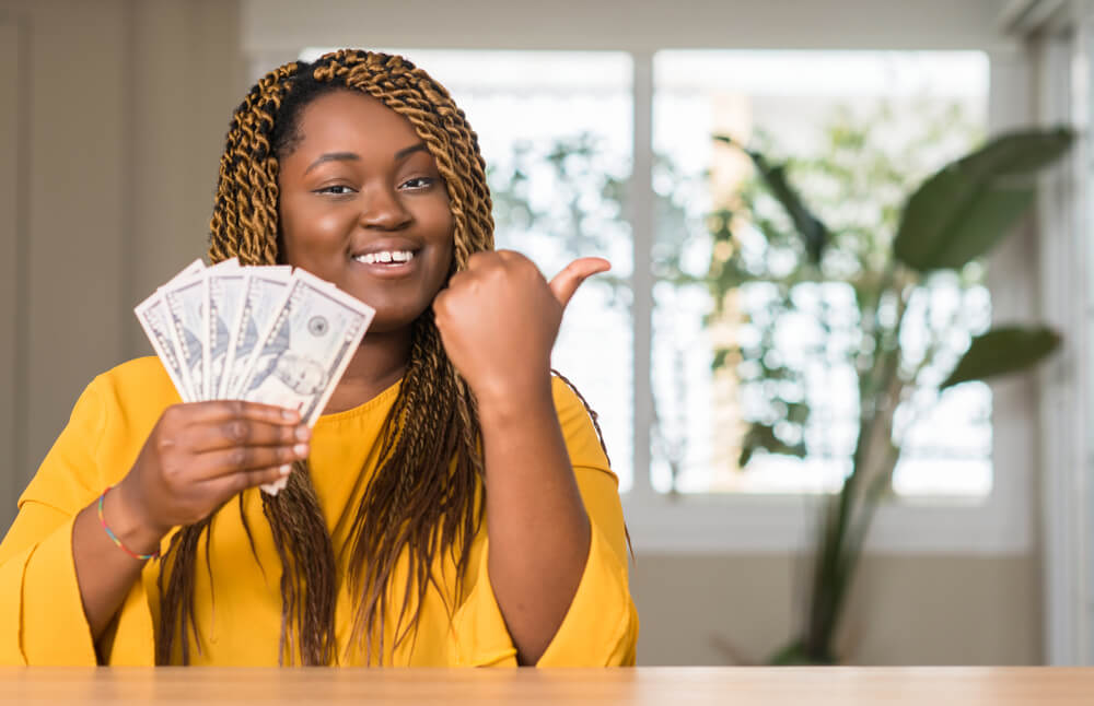 woman giving thumbs up and holding title loan cash in her hand