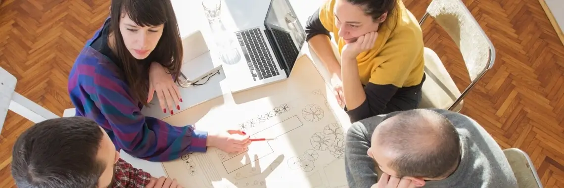 Team of people collaborating around a desk.