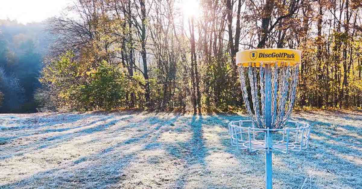Disc golf basket covered in ice shining in the sun