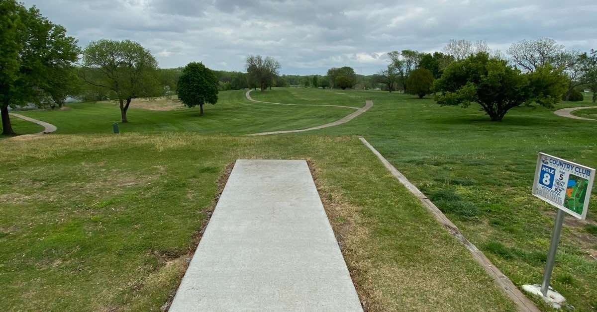 A concrete disc golf tee pad on a very open, golf course landscape