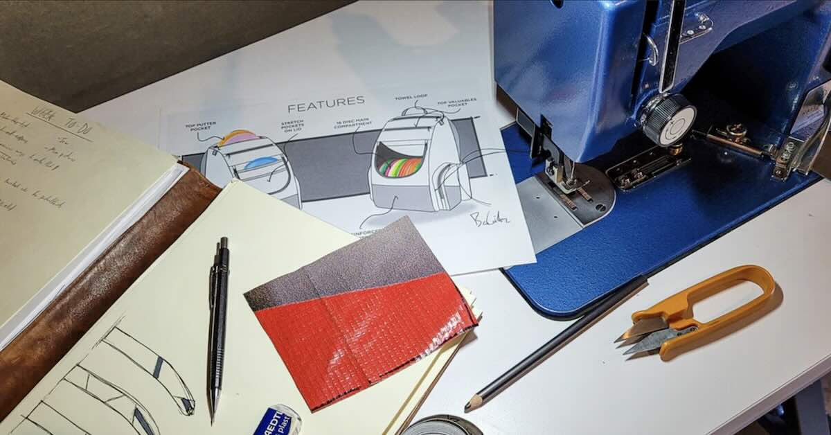 A table littered with designs, pencils, and a blue sewing machine