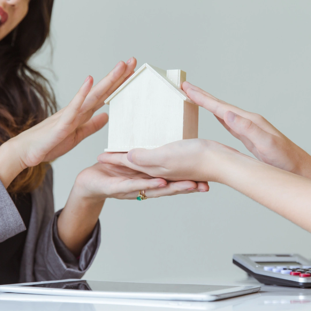 A realtor and a potential buyer holding a house.