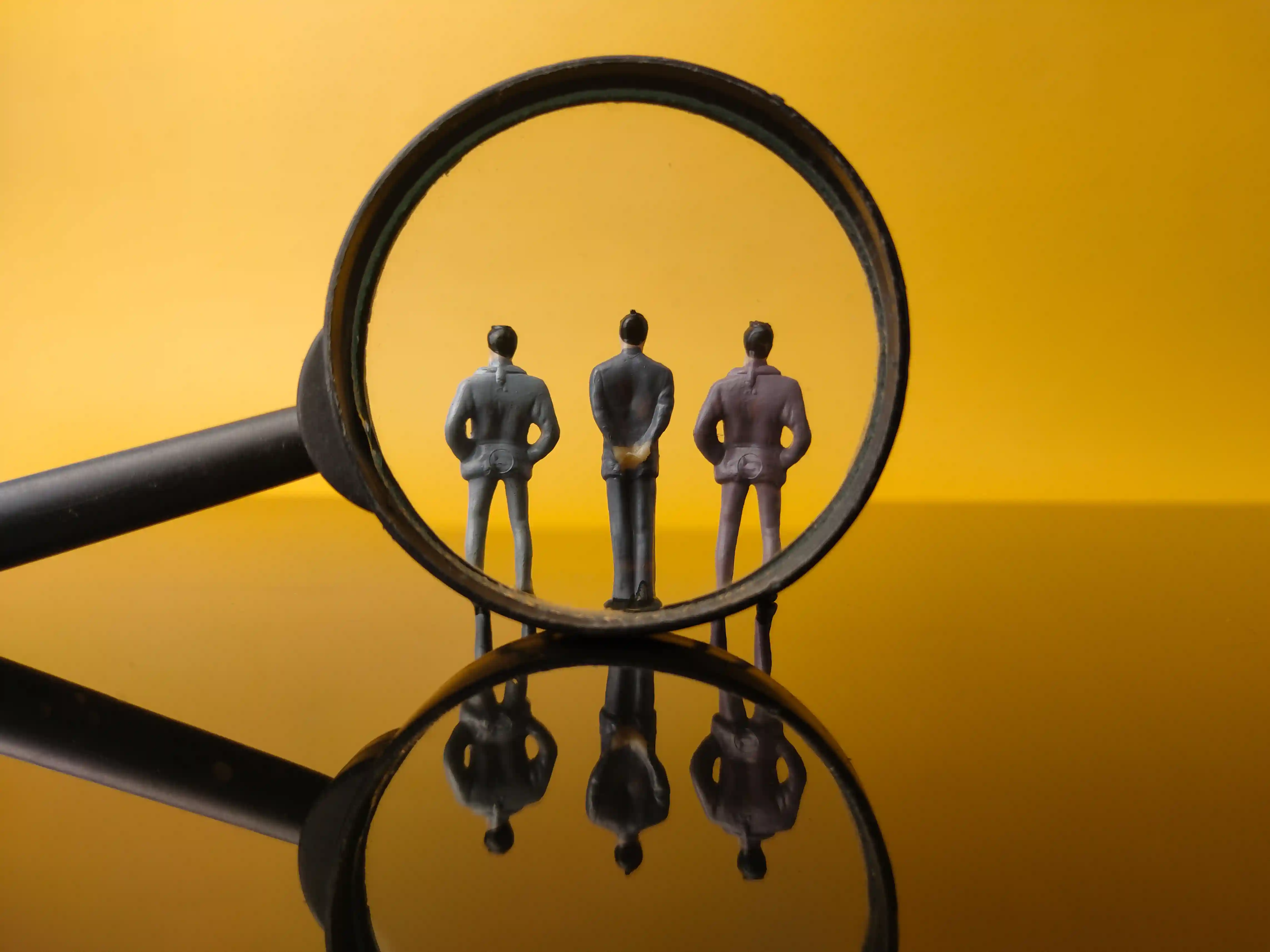 Magnifying glass focusing on professionals representing talent selection and verification