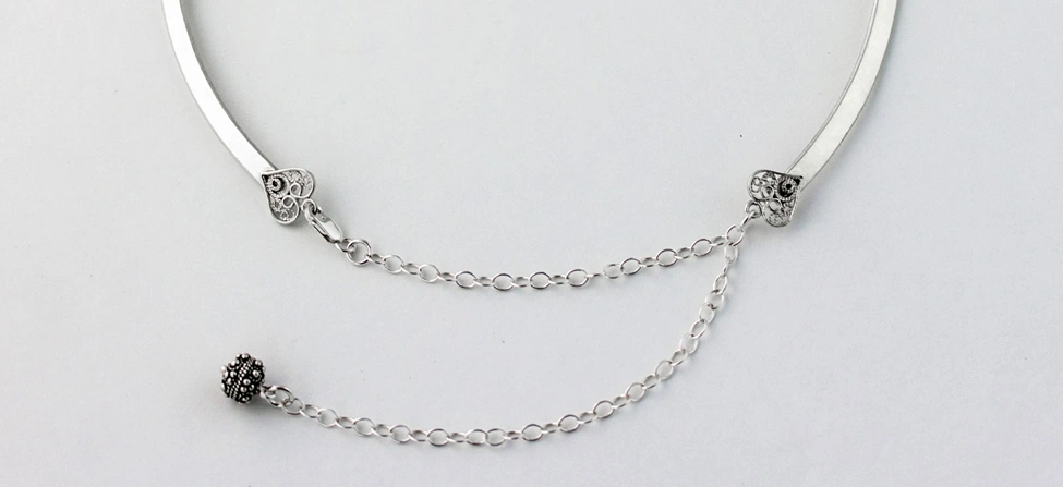 silver neck collar with decorative filigree hearts on the ends with chain and clasp 