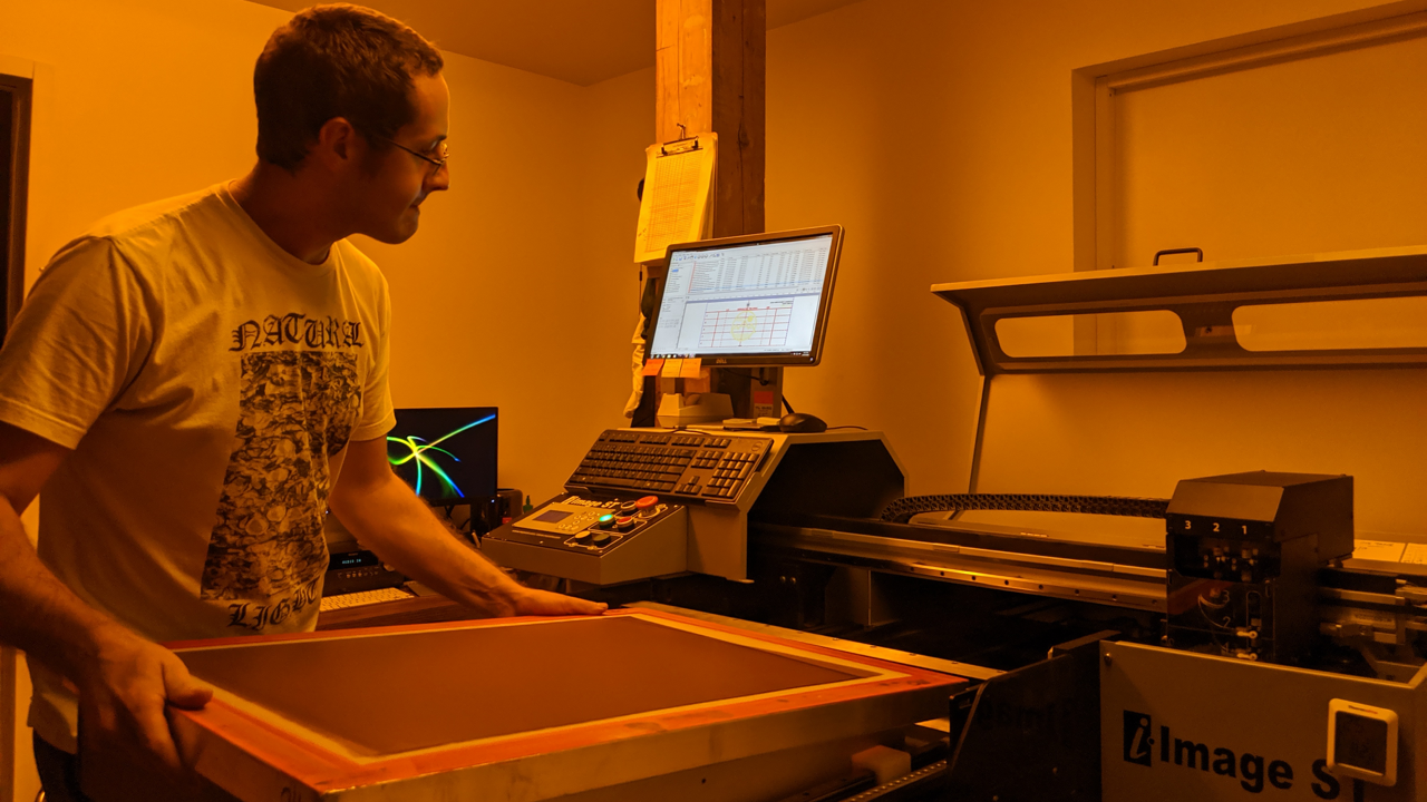 A computer-to-screen system (M&R i-Image) with a screen technician loading a screen printing screen.