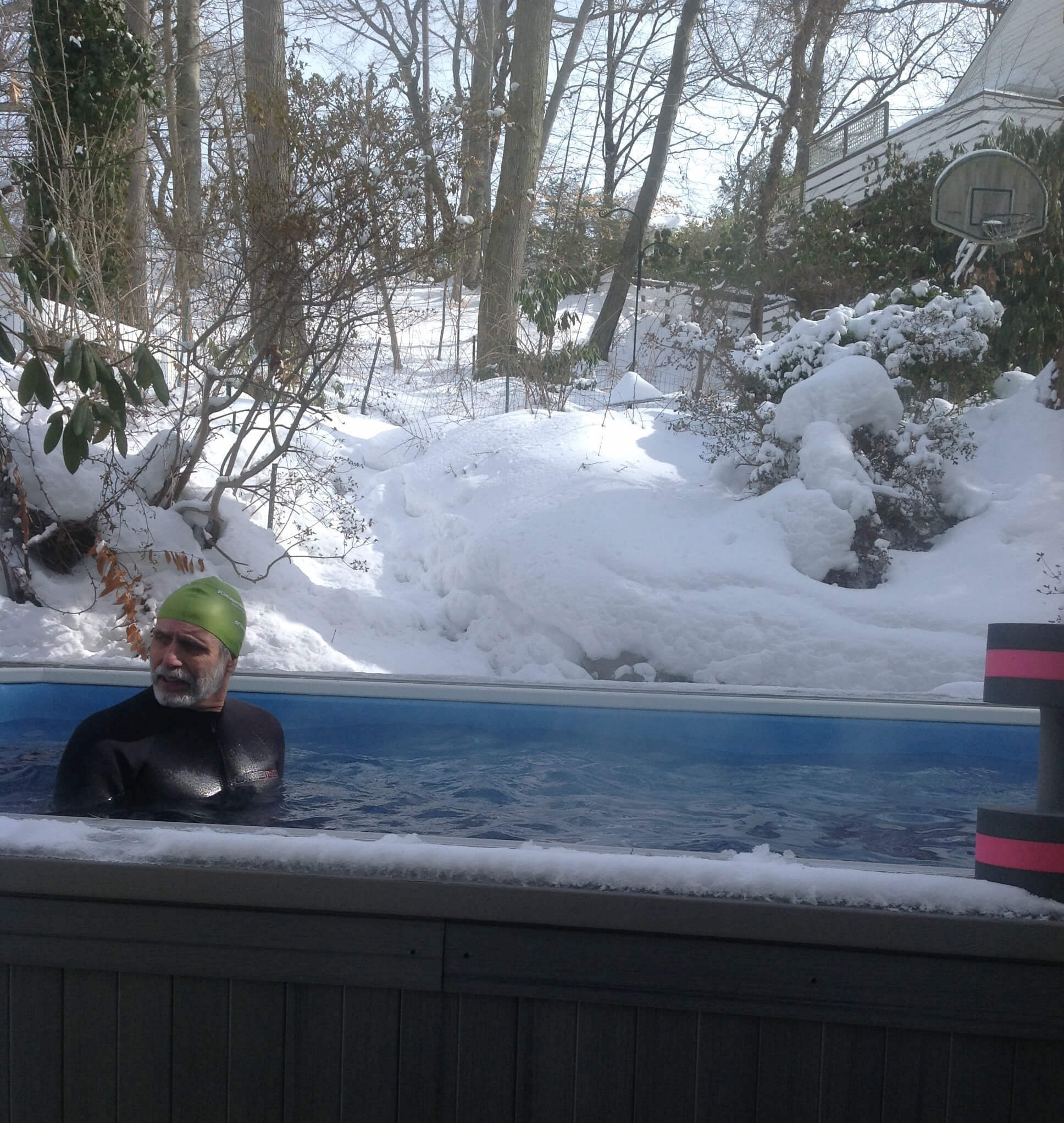 A swimmer in a wetsuit in the Endless Pools swimming machine after snowfall.