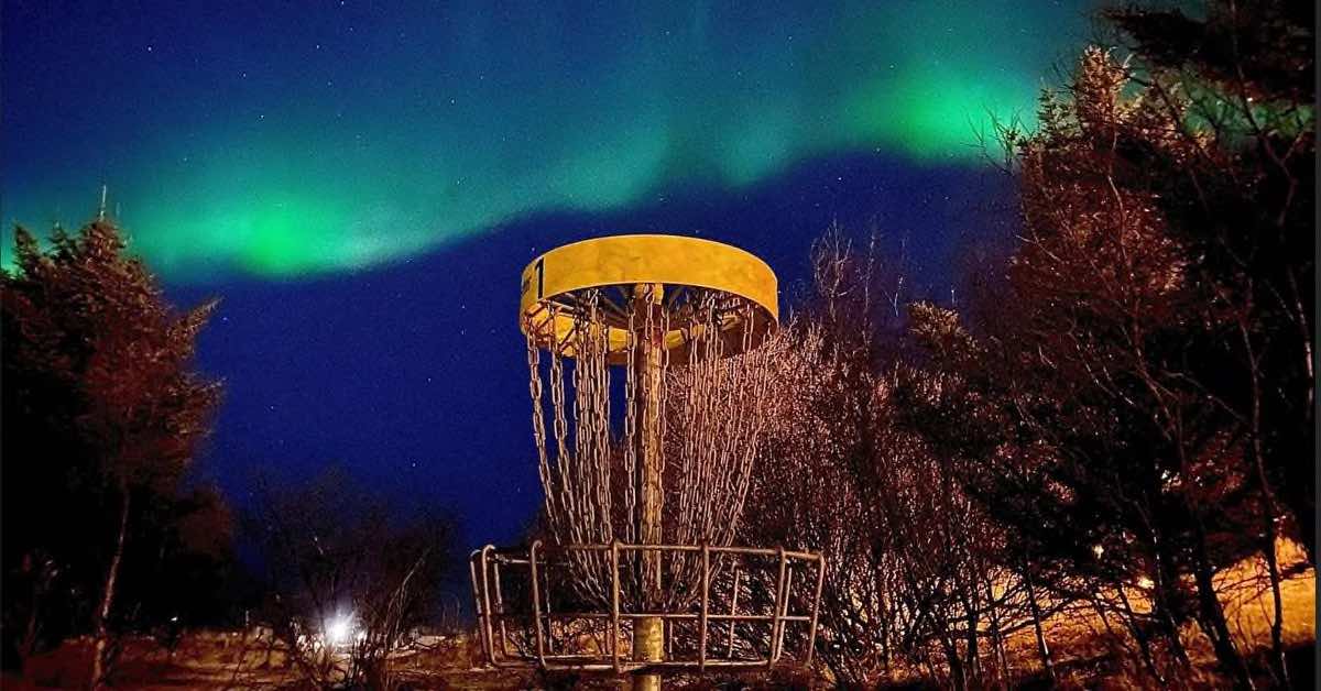 Disc golf basket with the northern lights behind