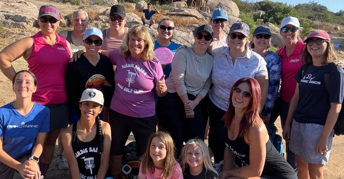 A group of women pose for a photo with disc golf gear