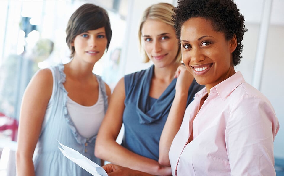 three women in an office looking directly at the camera