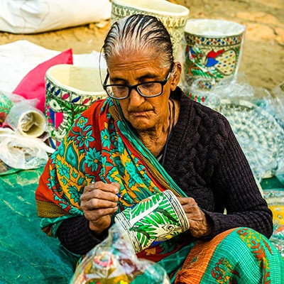 A woman sitting and painting pottery