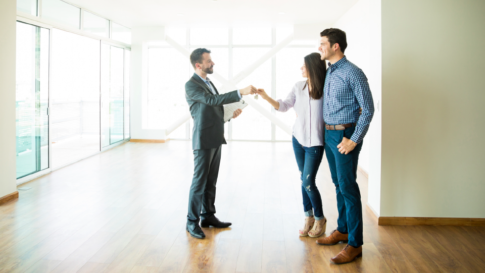 Man passing keys to a couple in empty room