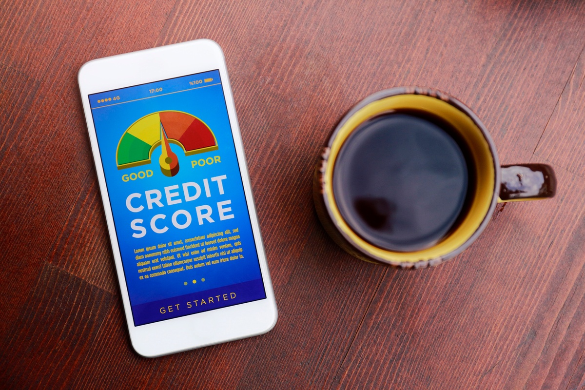 Mobile phone with a credit score meter on the screen, by a cup of coffee