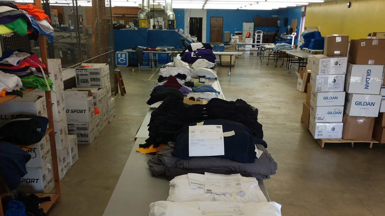 Setting up shirts and garments for screen printing at a print shop.