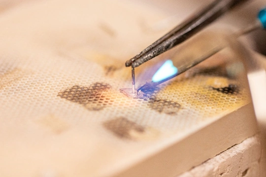 torch soldering an earring post to a small diamond shape