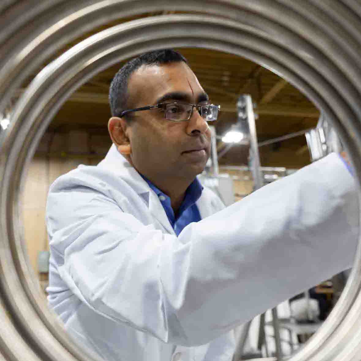 A scientist is viewed through a condenser coil
