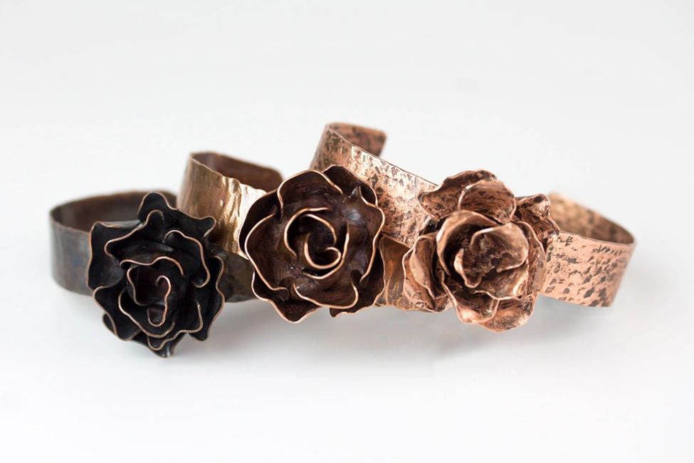 three copper cuff bracelets with 3d roses on top