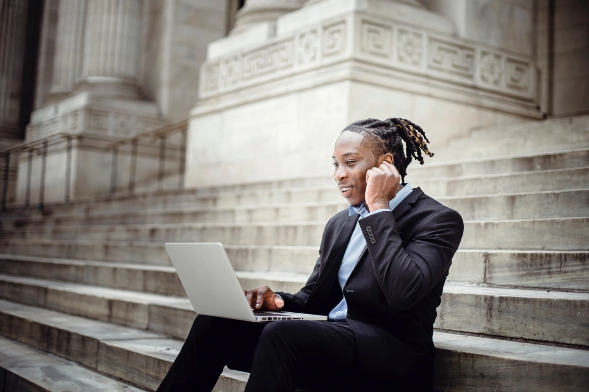 Business person using their laptop and accepting a call through ear piece.