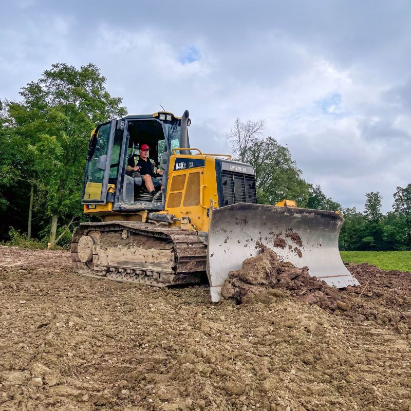 Cat D4K dozer pushing dirt on a construction site with an operator