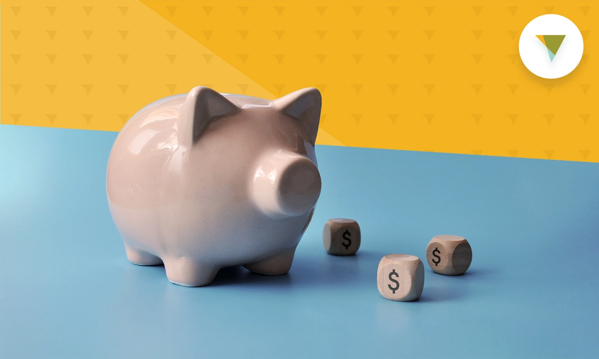 Pink piggy bank with dice around it with money signs printed on it.