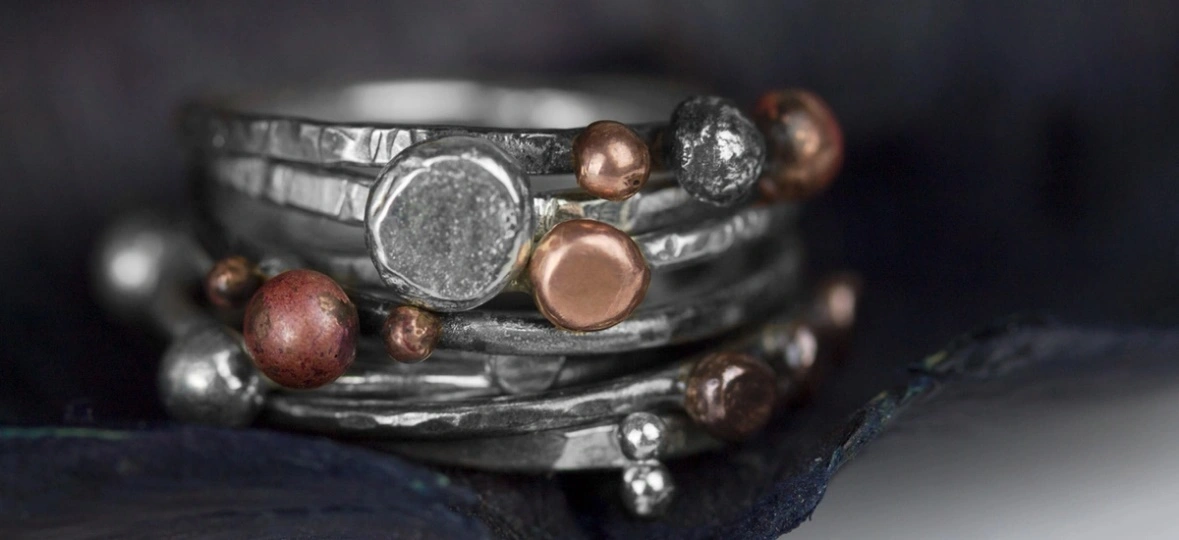 stack of silver rings with bronze and silver granules decorating them