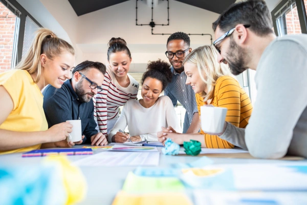 A team of office workers huddled around a project on a table.