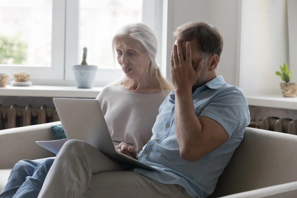 Pensioners at laptop looking upset