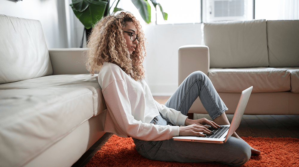 Woman sitting on floor typing on laptop