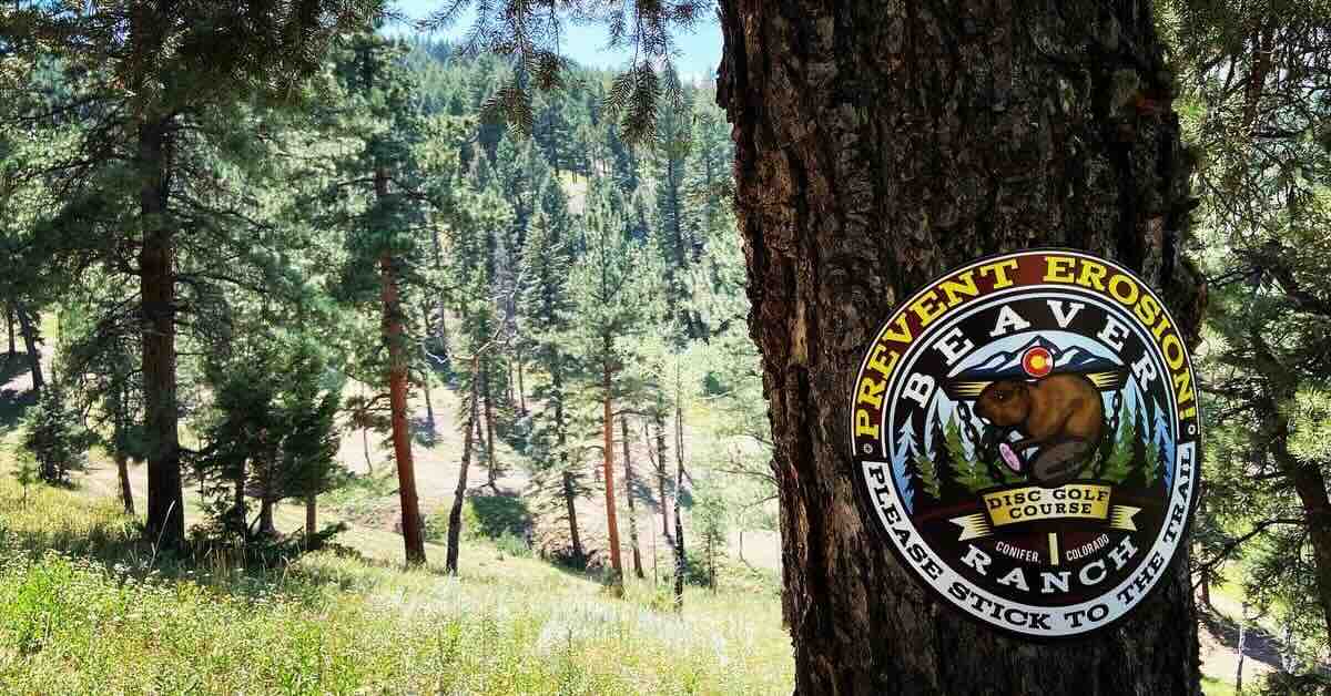 A sign on a tree asking disc golfers to stay on paths to help fight erosion
