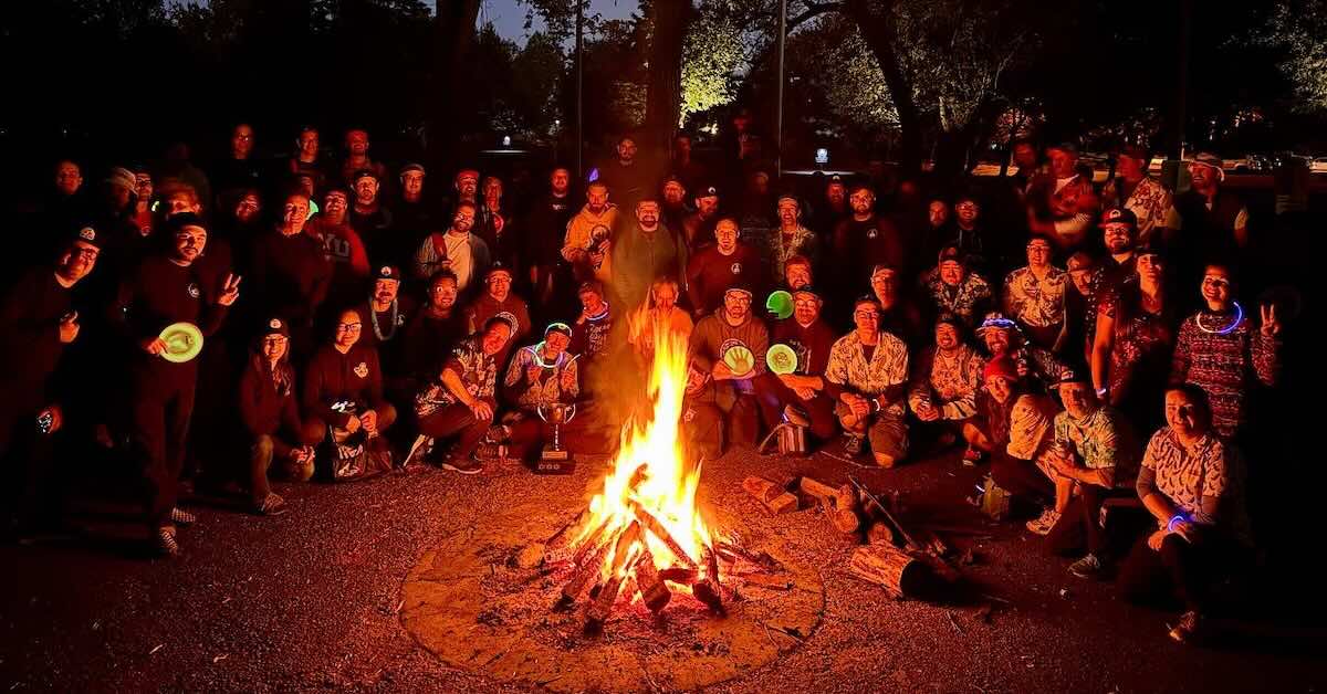A group of disc golfers gathered around a bonfire