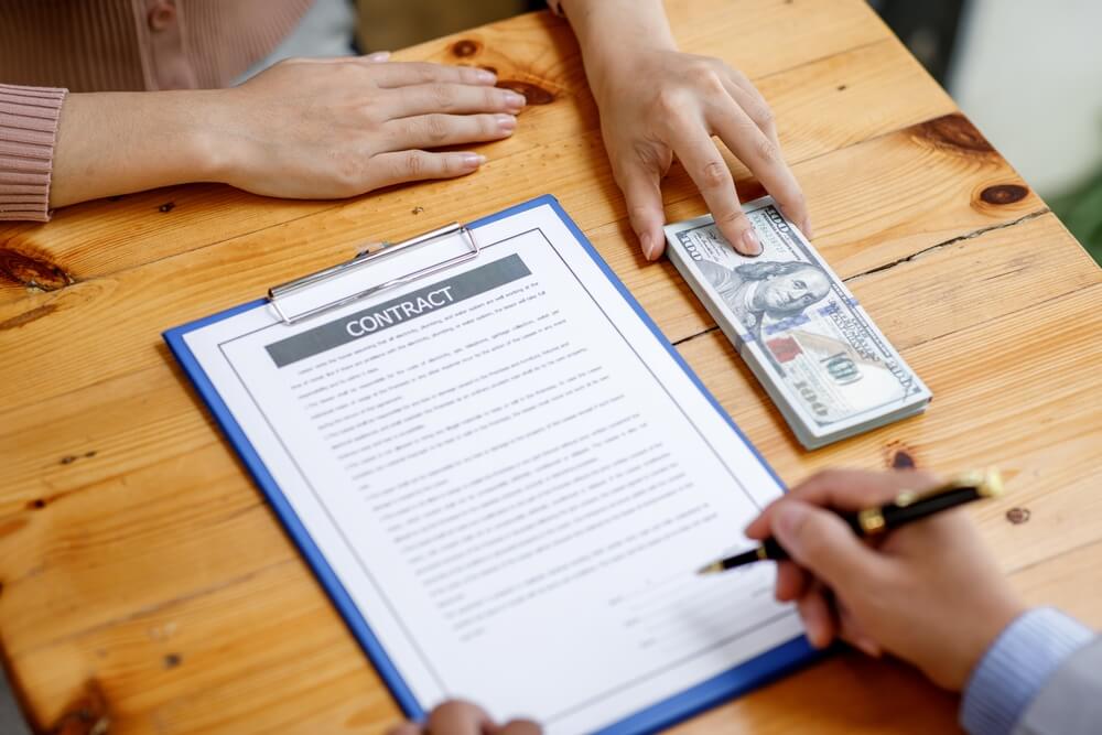 man signing a vehicle title loan agreement