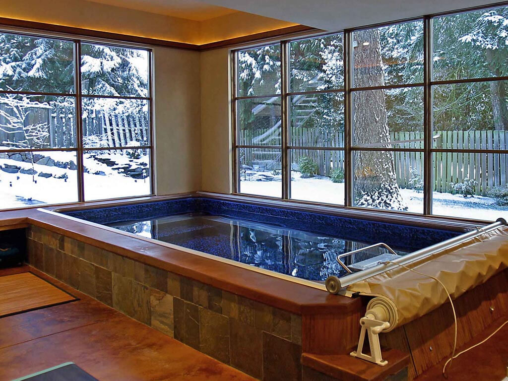 A partially inground Original Endless Pool with a snowy view.