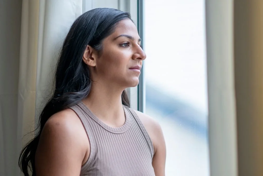 Woman gazing out window while contemplating IVF success rates.