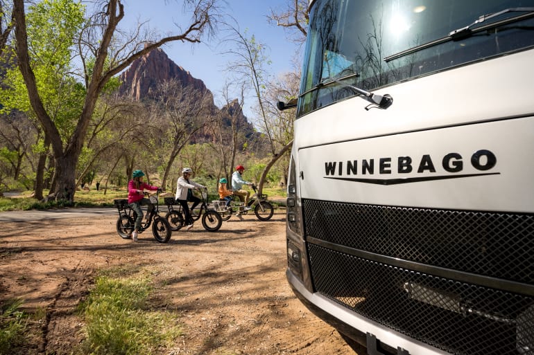 Family on bikes in front of Class A RV