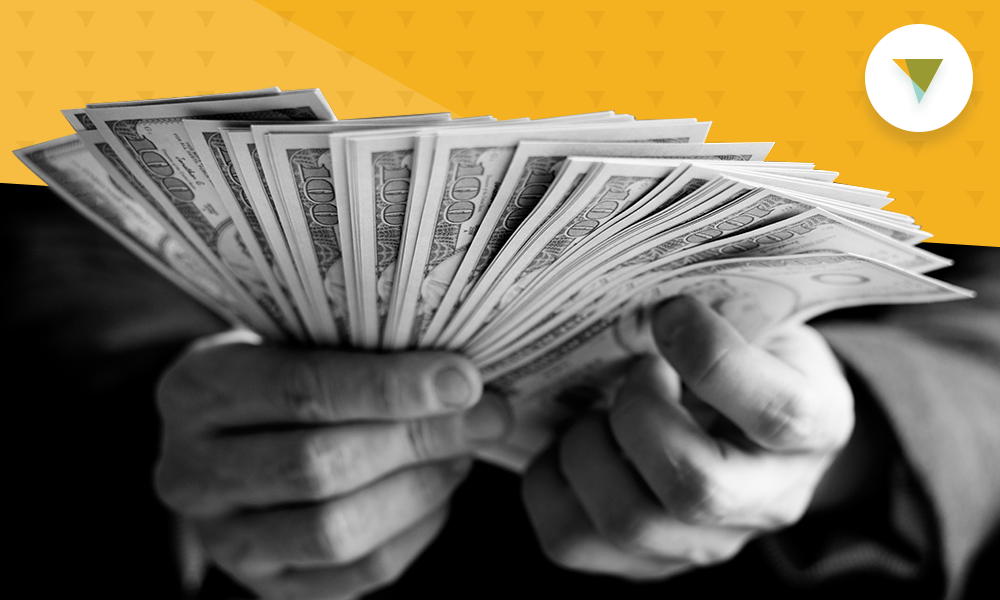 hands holding a stack of money fanned out.