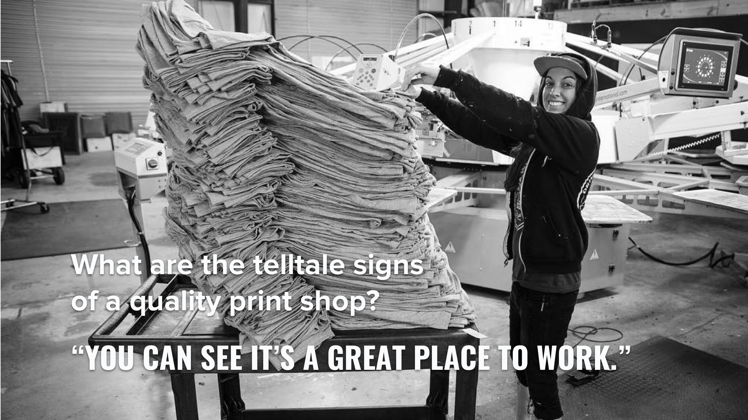 A screen printer with a large stack of shirts.