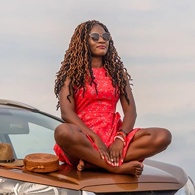 Woman sitting on her car peacefully.