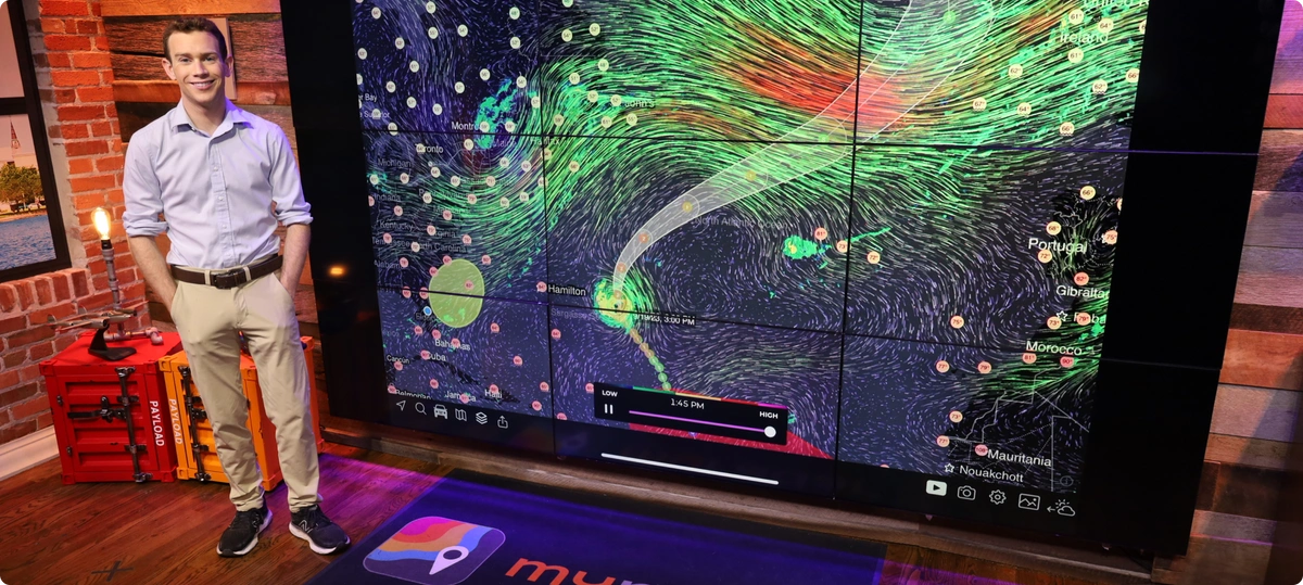 Meteorologist standing in front of screen with weather patterns