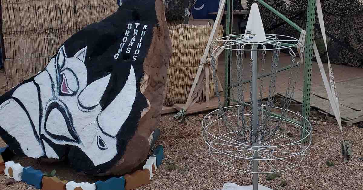 Disc golf basket next to a black rock