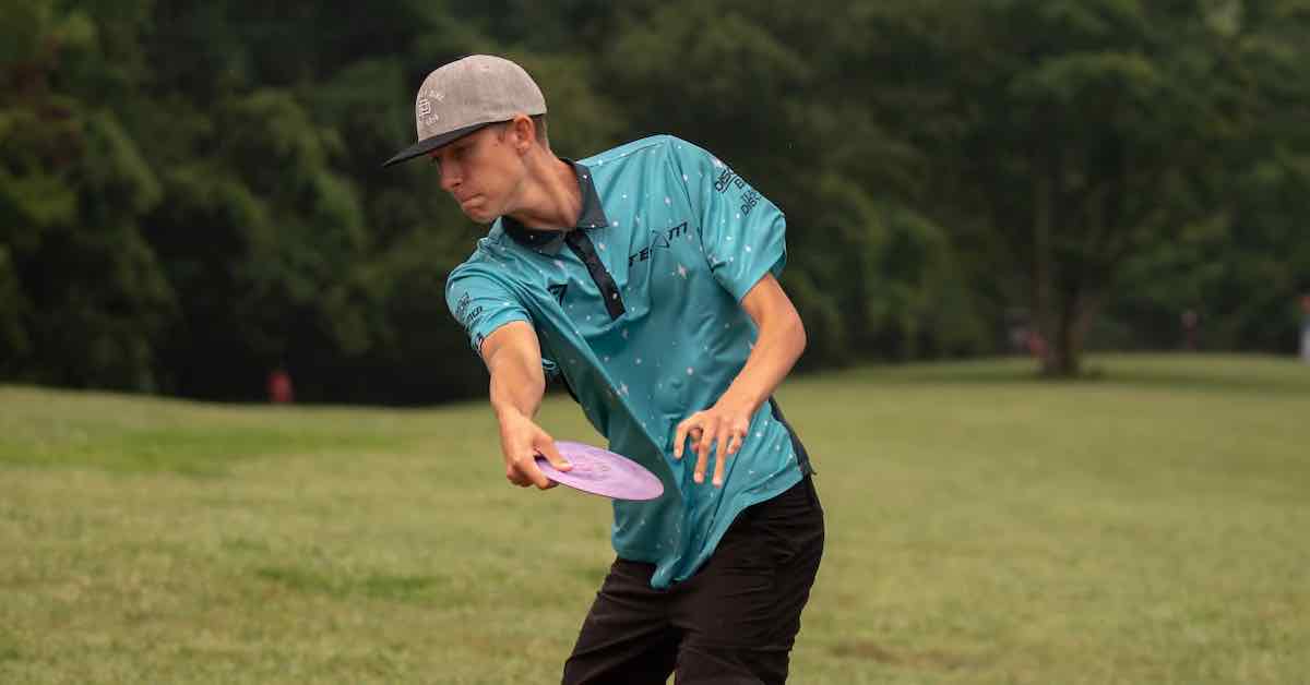 A lanky young man at full reach back during disc golf throw