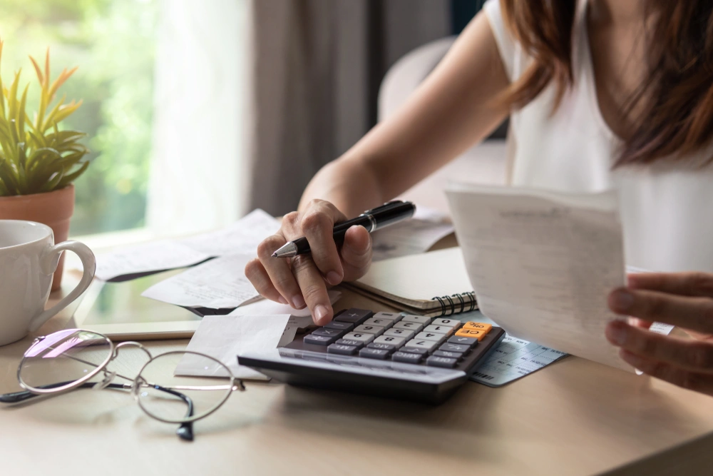 Woman sat at the table with receipts and a calculator