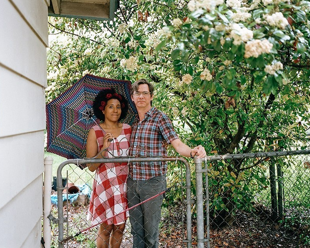 couple standing behind fence