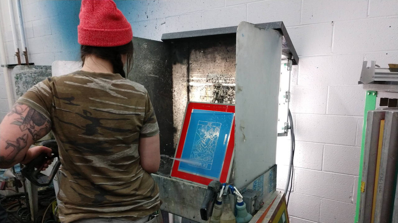 A woman cleans a screen used for screen printing at Barrel Maker Printing