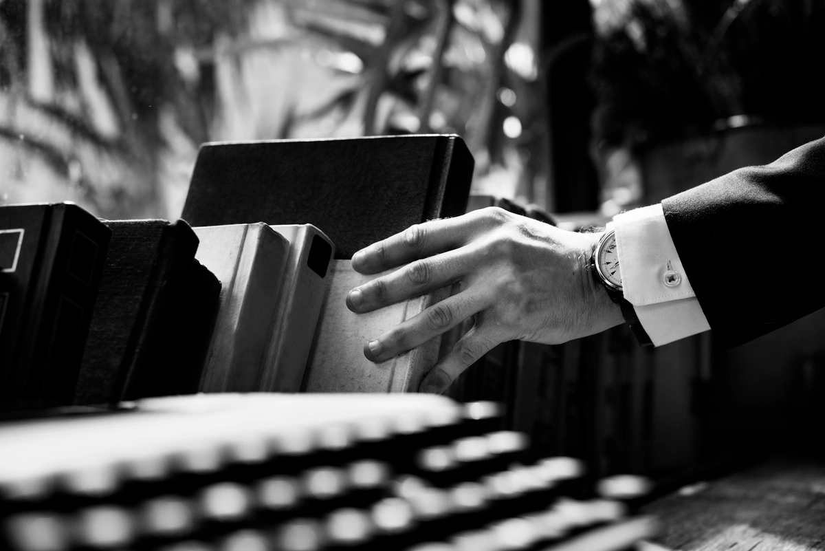 Close-up of a hand reaching for a book from a shelf, symbolizing the search for knowledge and information.