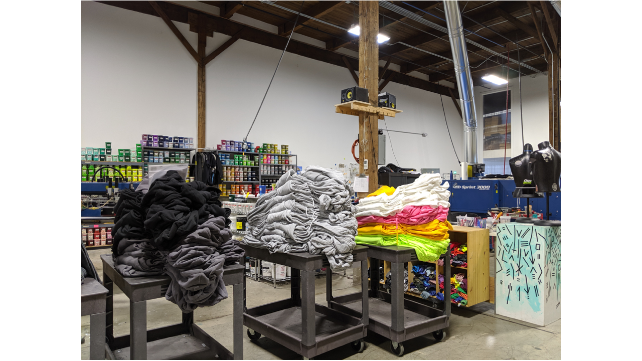 Dozens of hoodies on plastic carts waiting to be screen printed at a print shop.