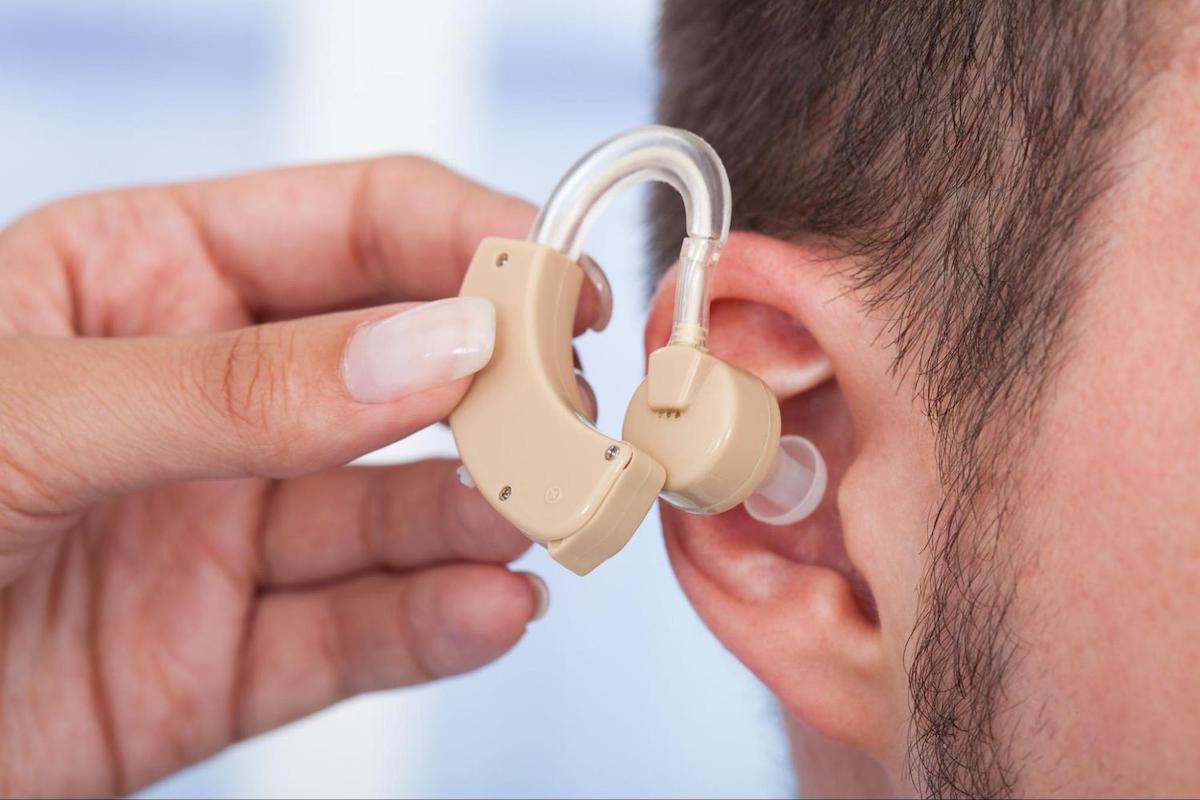 online hearing aids: person putting in a hearing aid in someone's ear