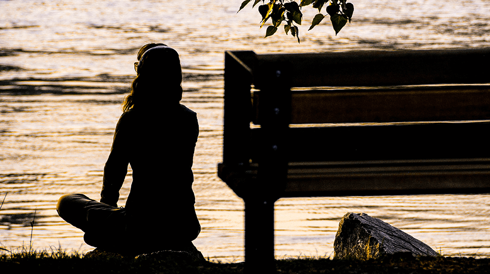 Woman meditating next to lake