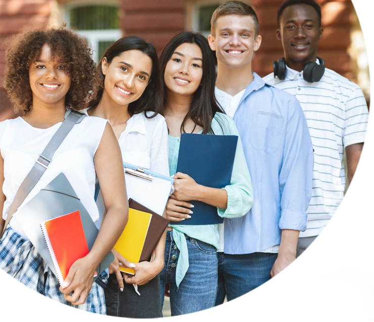 Multiethnic group of students standing near college building, posing at camera and smiling