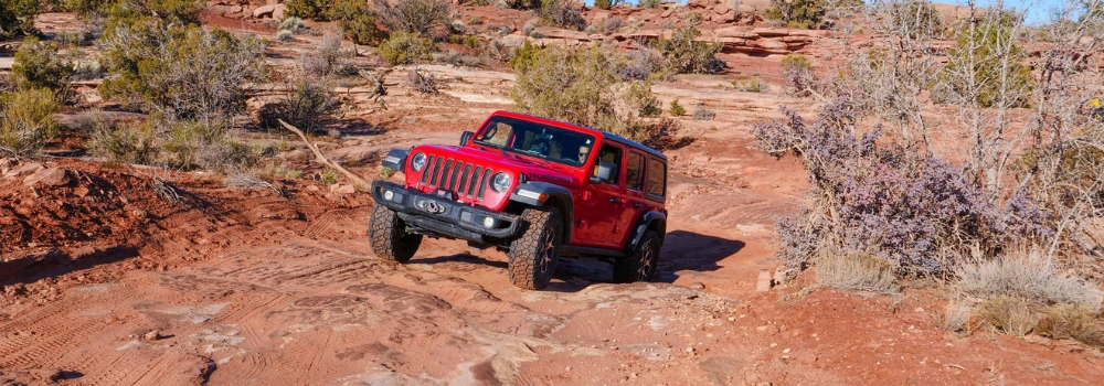Red Jeep driving up Gemini Bridges